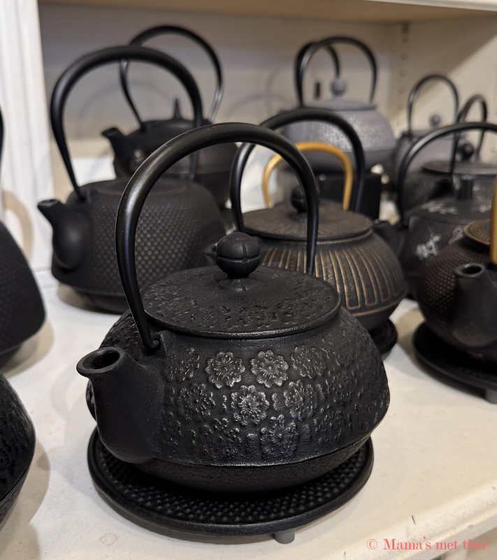 Zwarte gietijzeren theepot met gedetailleerd bloemenreliëf op onderzetter in een theewinkel