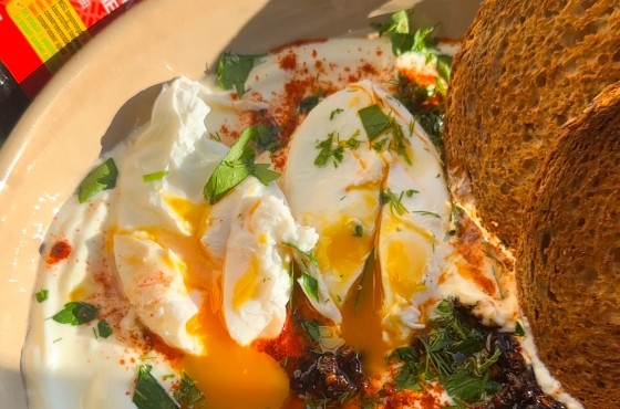 Gepocheerde eieren op yoghurt met chili-olie en brood