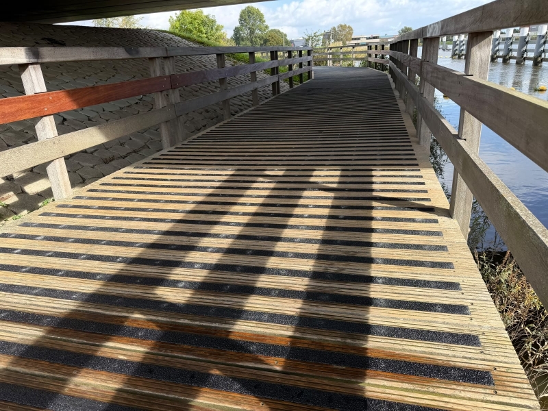 Vlonderpad onder de Gouderakse brug met zwarte antislipstrips over elke plank, na de montage door De Antislip Expert