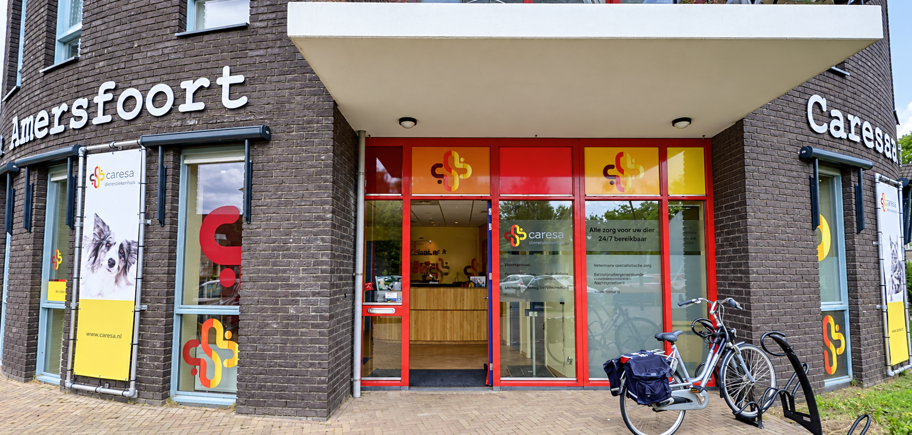 Entree van Dierenarts Vathorst met rode kozijnen, Caresa-belettering en fietsen voor het pand.