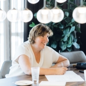 een vrouw schrijft vrolijk in haar schrift omdat ze een podcast gaat laten maken