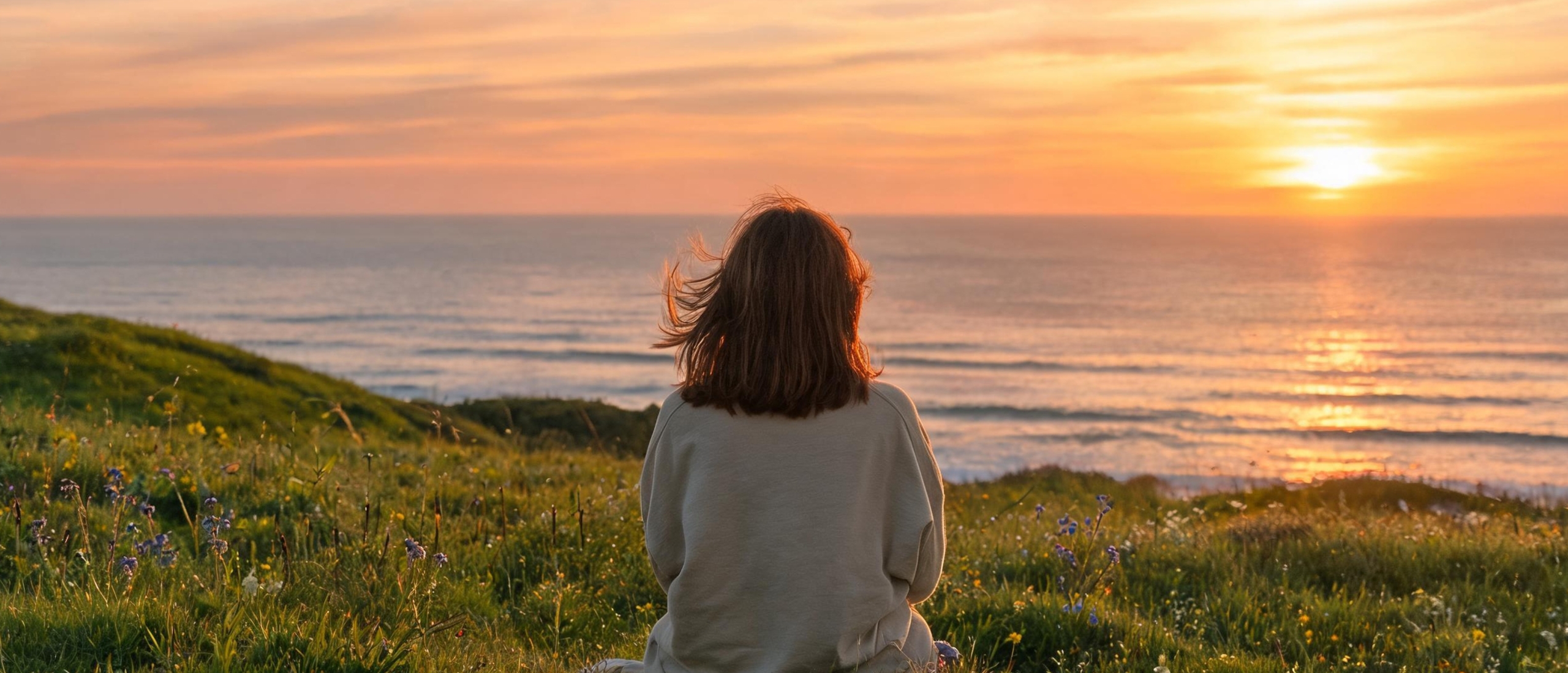 Vrouw zit rustig in de natuur en kijkt uit over zee