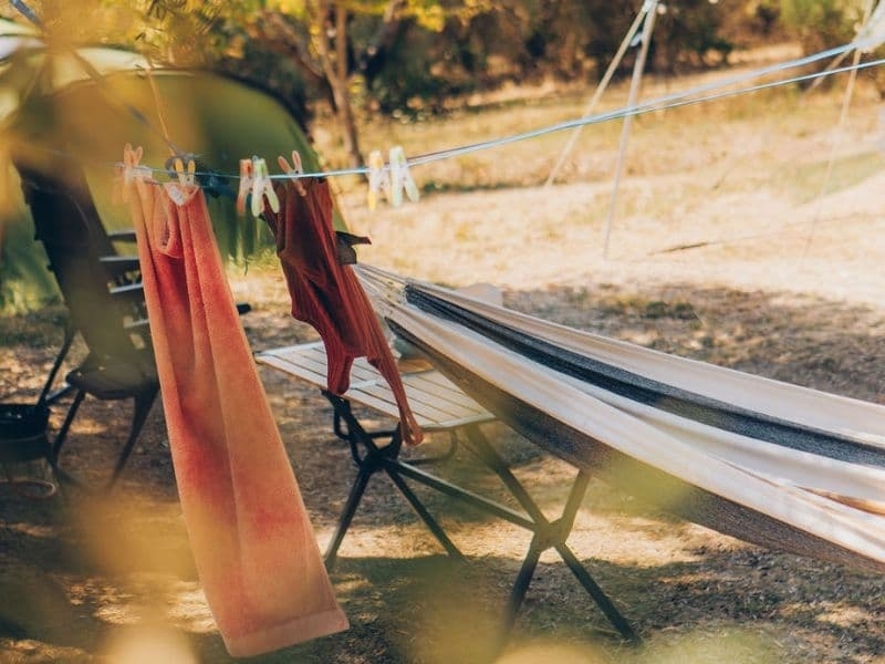 Hangmat, campingtafel en een waslijn met handdoeken op een zonnige kampeerplek bij Camping Vista Fermo