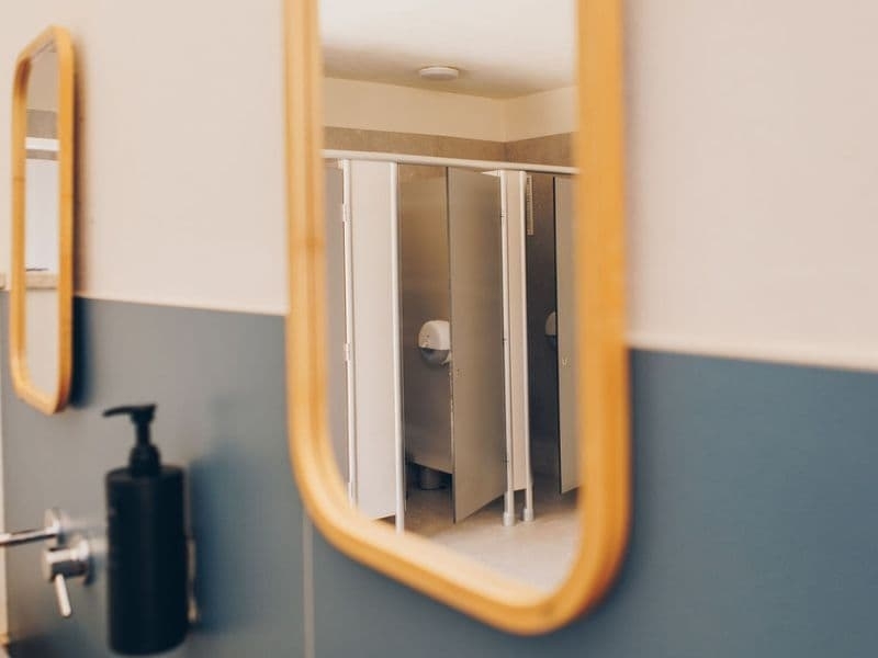Spiegel met houten rand in het sanitairgebouw van Camping Vista Fermo, met daarin de toiletten