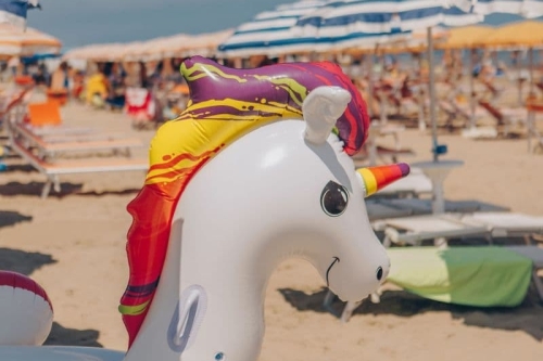 Opblaasbare eenhoorn op het zandstrand met parasols aan de Adriatische kust, op een kwartiertje van Camping Vista Fermo