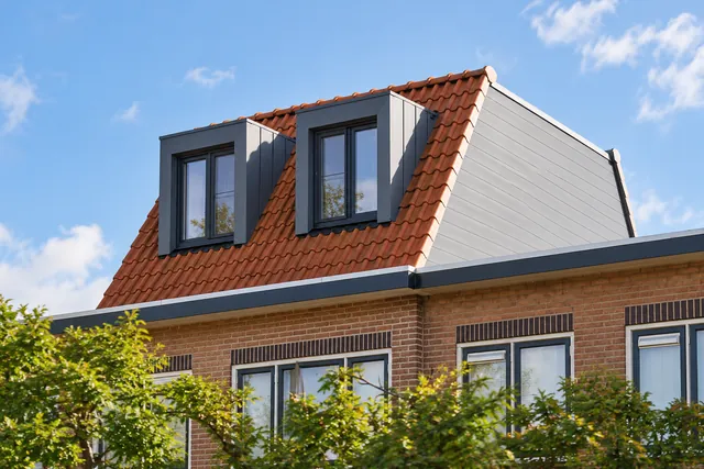 Dakopbouw met twee donkere dakkapellen en rode dakpannen in Hoorn
