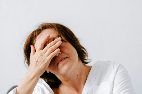 Vermoeide vrouw in de overgang met haar hand voor haar ogen