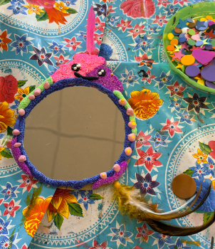 Blauw-paars spiegeltje met een roze foamklei-monstertje bovenop met wiebeloogjes en een roze veertje