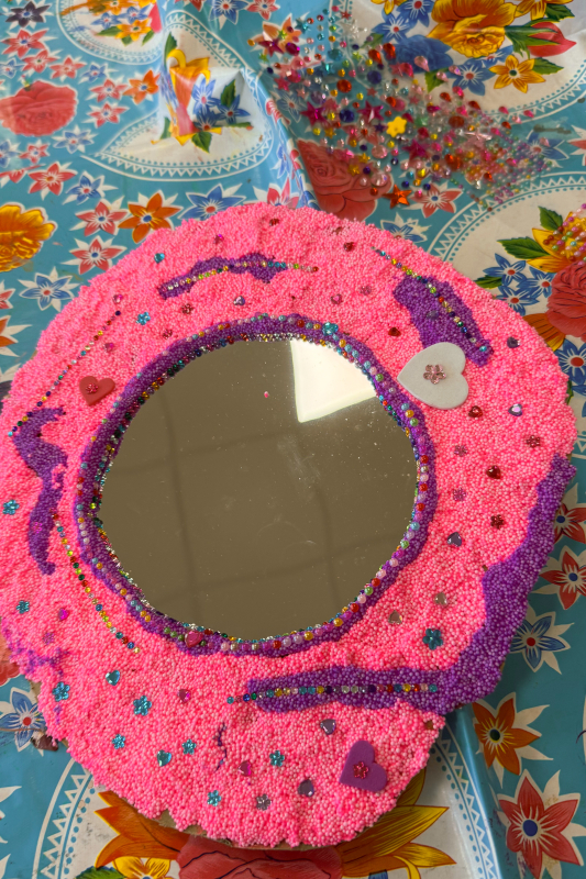 Roze prinsessenspiegel met strass Rond spiegeltje versierd met roze en paarse foamklei, strass-steentjes en hartjes — resultaat van de spiegeltjes versieren workshop