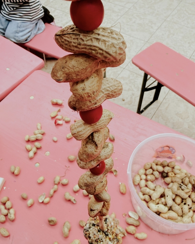 Kind stelt pinda slingers samen met rode ballen op elkaar in de creatieve kinderhoek van het herfstevenement winkelcentrum