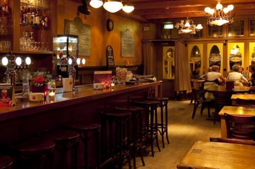 Café Piet Pann in Schagen Lange houten bar met barkrukken en tafeltjes met kaarsjes in Café Piet Pann in Schagen