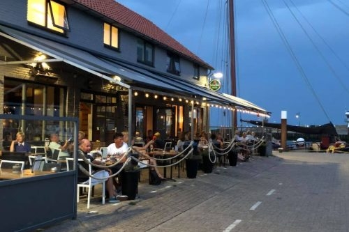 Eetcafé De Kombuis op Texel Terras met lichtsnoeren onder de luifel aan de haven bij Eetcafé De Kombuis in Oudeschild op Texel
