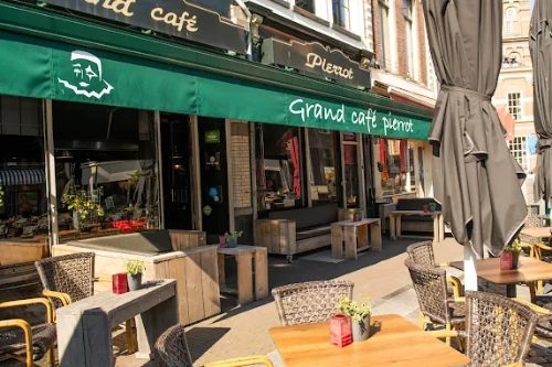 Gevel van Grand Café Pierrot met groene luifel en een terras met rieten stoelen aan de Houtmarkt in Zutphen