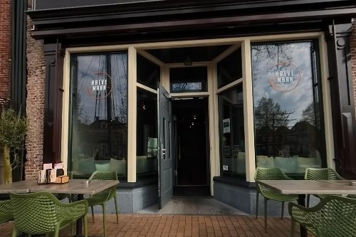 Gevel van café-restaurant Halve Maan aan de Diepswal met groene terrasstoelen in Dokkum