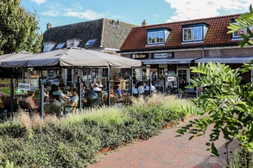 HeerlijkZo in Renesse Vol terras met grijze parasols voor brasserie HeerlijkZo in de dorpskern van Renesse