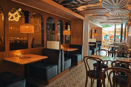 Zitbanken, bistrotafels en houten wanden met boogspiegels bij St. Tropez, met achterin het terras aan de Brink in Deventer