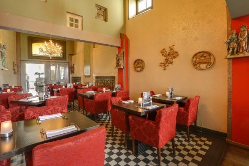 Eetzaal van restaurant Vaticano met rode stoelen, een kroonluchter en een zwart-witte tegelvloer in Zutphen