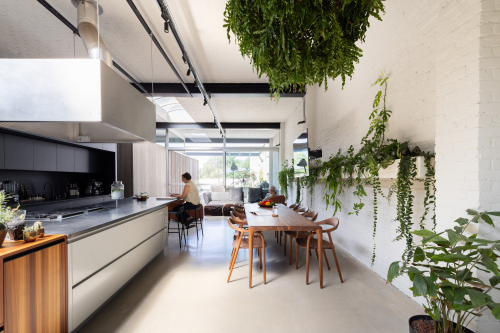 Appartement met een uitgesproken, gelaagd interieur Woon- en eetruimte van een appartement met veel groen, hout en zichtbare constructie, waarin patroon en textuur het interieur dragen