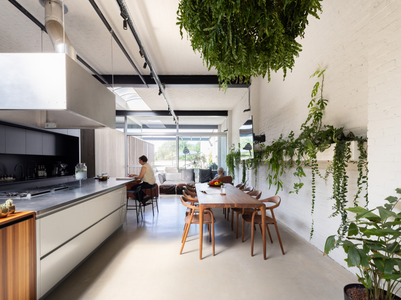 Woon- en eetruimte van een appartement met veel groen, hout en zichtbare constructie, waarin patroon en textuur het interieur dragen