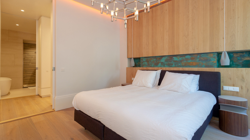 Slaapkamer met houten kastenwand en aangrenzende badkamer Interieurontwerp — slaapkamer — bed met houten kastenwand en zicht op de badkamer