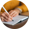 Vrouw in gele trui schrijft in een notitieboekje